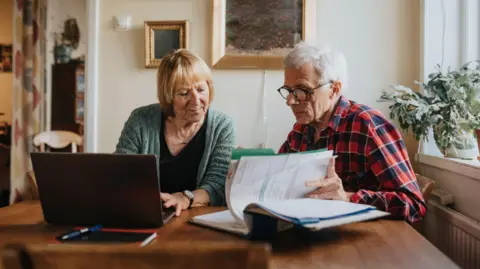 Getty Images Retired couple looks at their finances on paper and a laptop